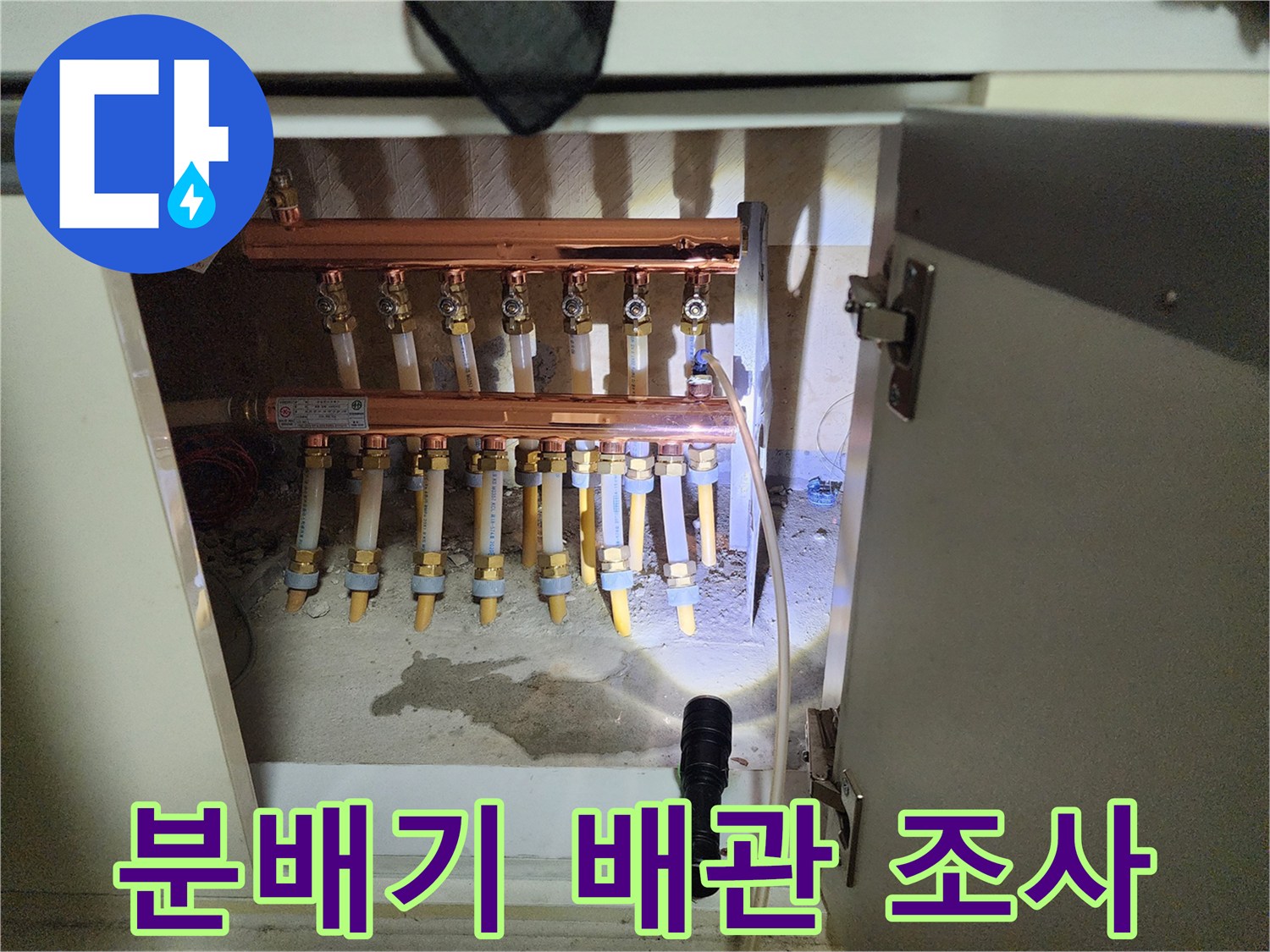 주방 하부장의 분배기와 연결된 다수의 배관들을 촬영한 사진입니다.