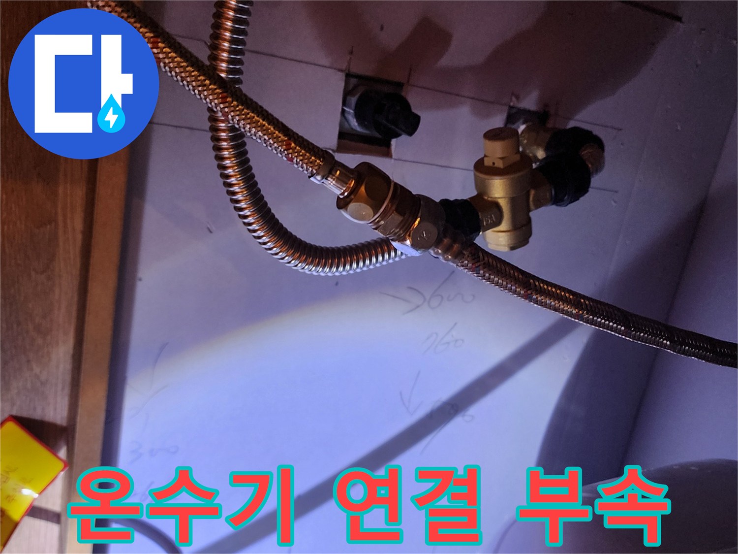전기 온수기 본체와 연결된 금속 호스 및 황동 어댑터의 근접 촬영