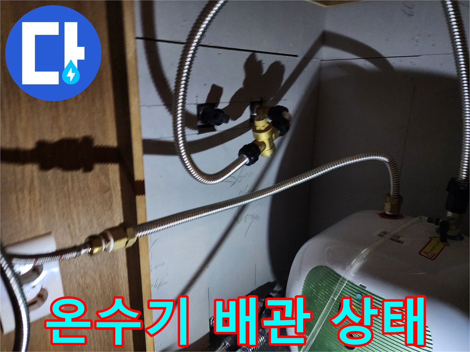 주방 싱크대 하부에 설치된 전기 온수기와 급수 배관