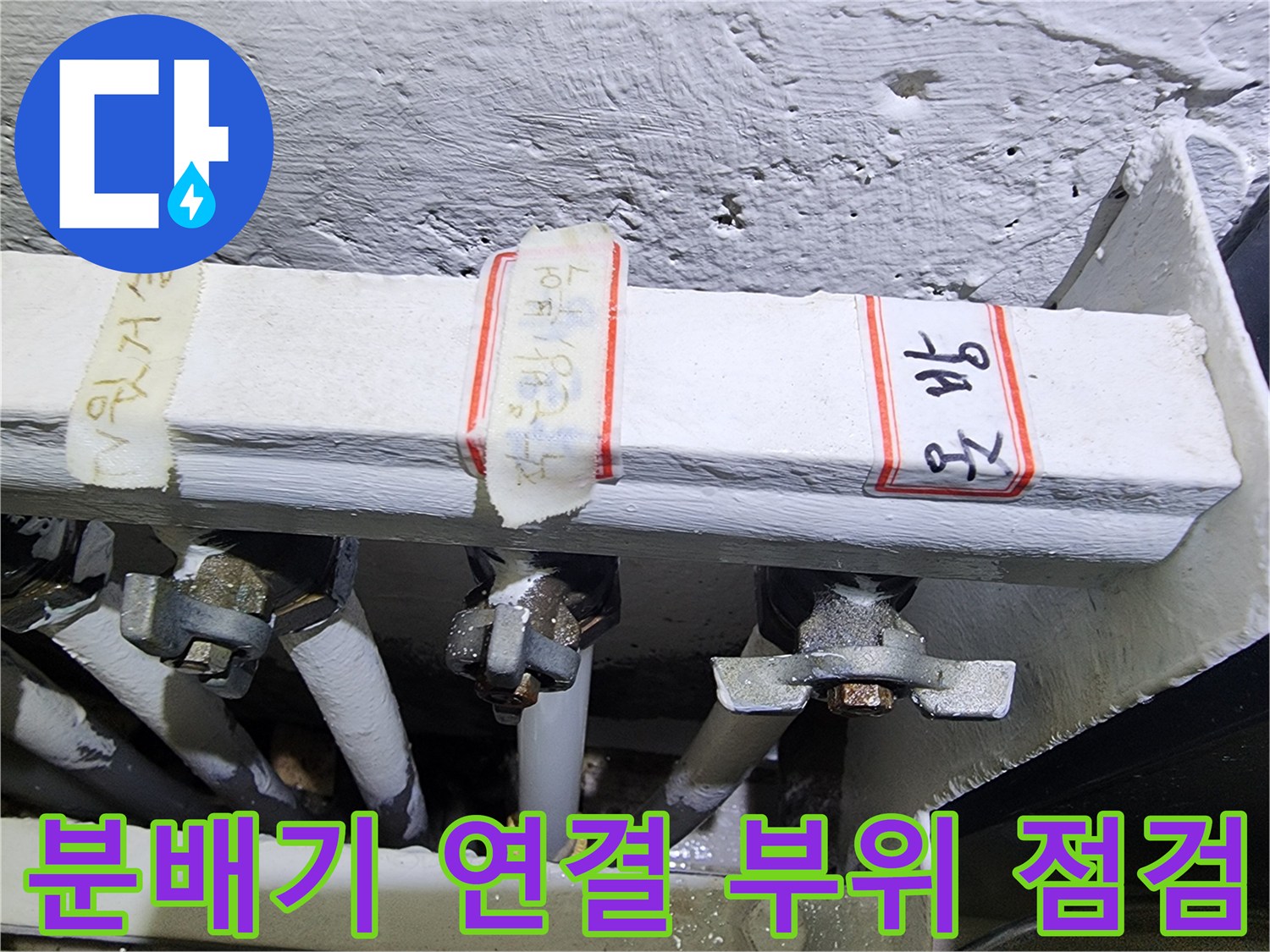 보일러 분배기의 배관 연결 부위를 정밀하게 점검하는 모습
