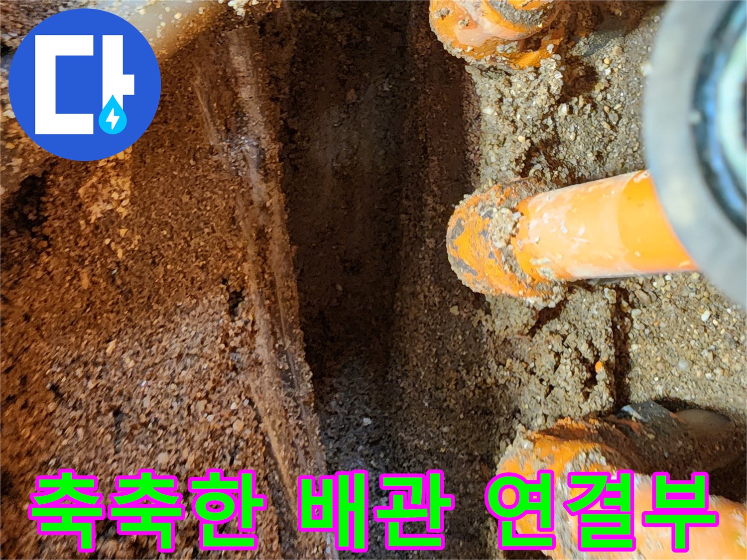 누수로 인해 습기가 가득 찬 오렌지색 배관과 주변 흙