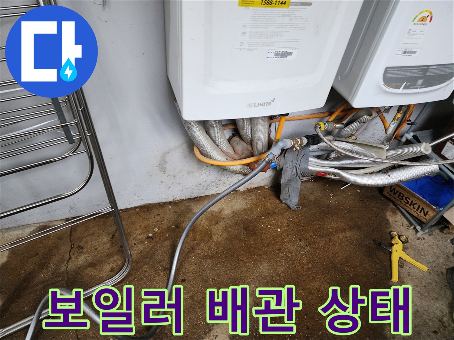 보일러실 하단에 노출된 배관과 분배기 연결 부위의 상태를 보여주는 사진입니다.