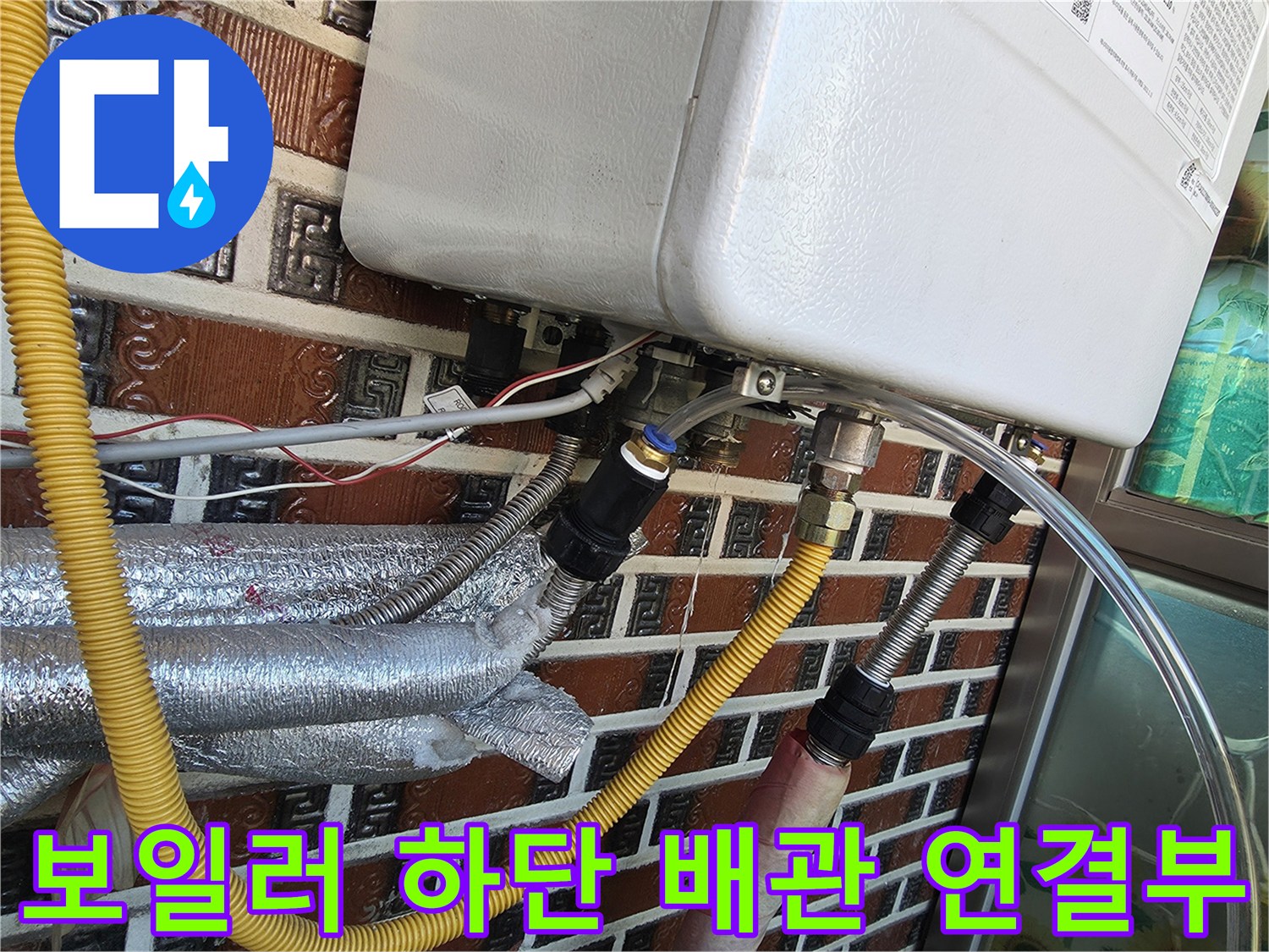 보일러 하단부에 연결된 노란색 보온재 배관과 금속 커플링 상세 모습