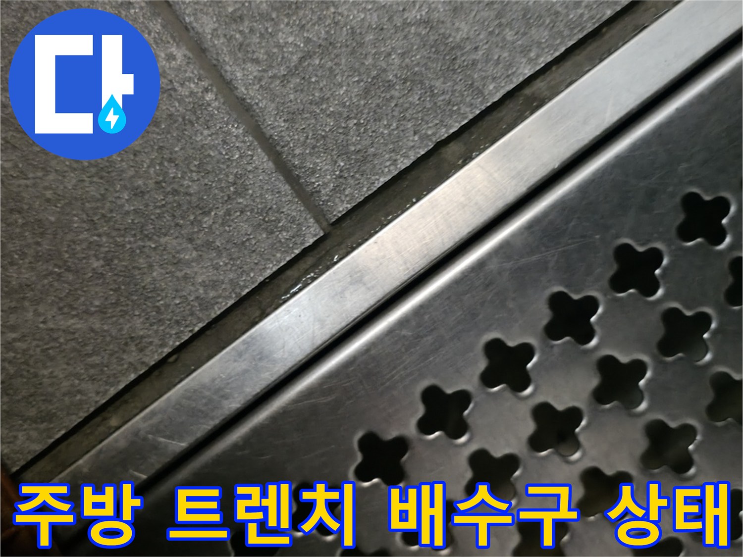 상가 주방의 스테인리스 트렌치 배수구와 타일 바닥 모습