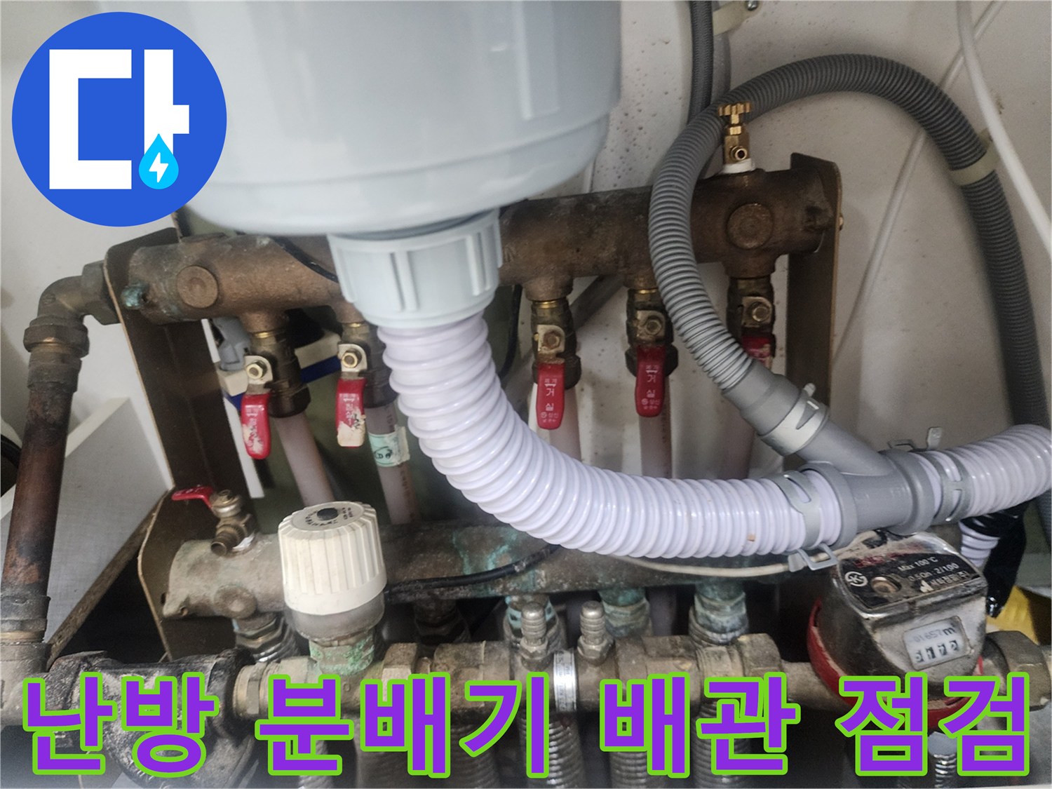흰색 호스와 금속 밸브가 복잡하게 연결된 난방 분배기 근접 사진