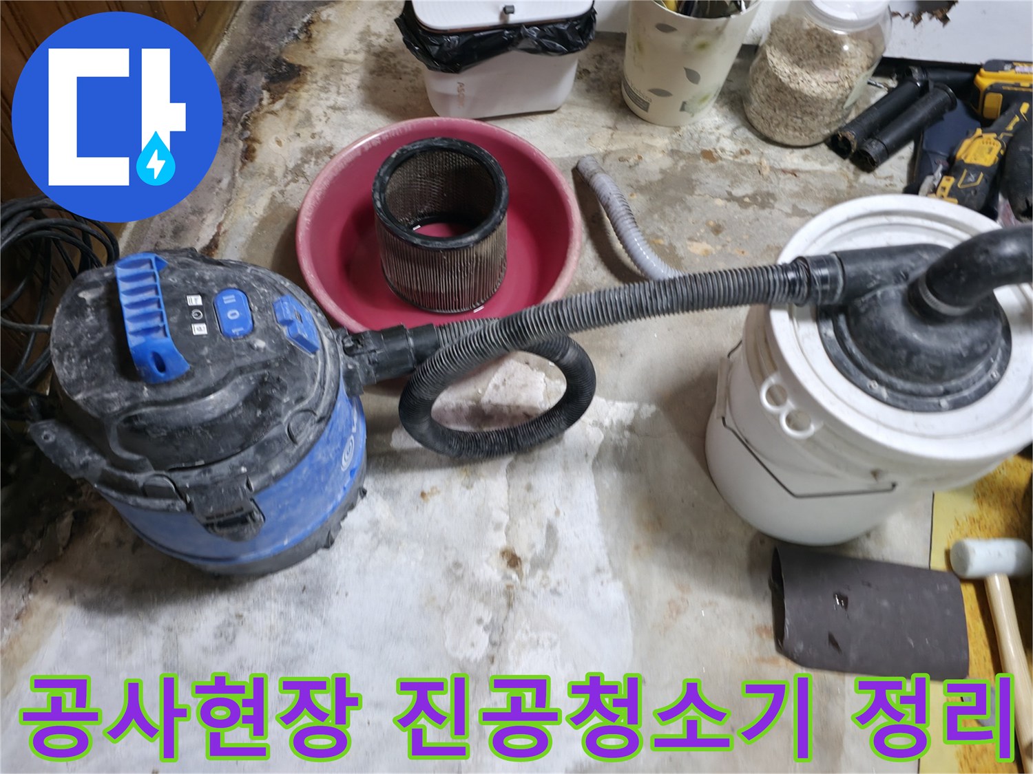 누수 공사 후 잔해물을 제거하기 위해 사용 중인 산업용 청소기와 작업 도구들입니다.