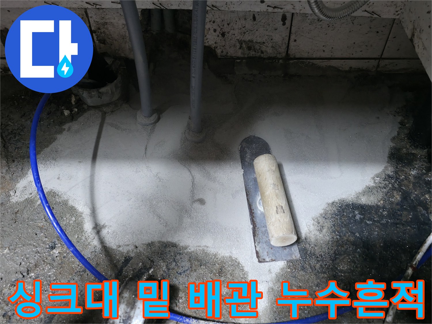 물기가 번져 있는 싱크대 하부 바닥과 배관 구조물