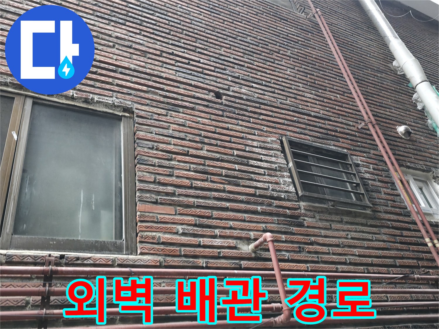 수직으로 배치된 외부 배관과 벽돌 외벽의 접합 상태
