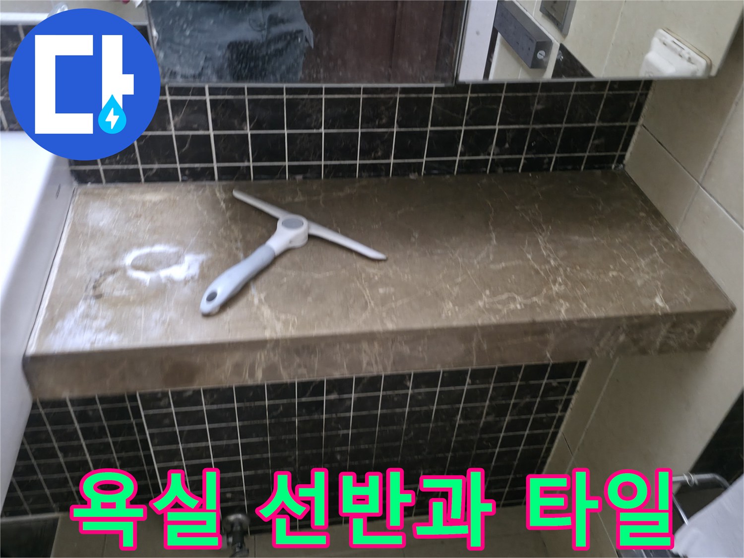 어두운 색상의 욕실 타일과 세면대 옆 선반 모습