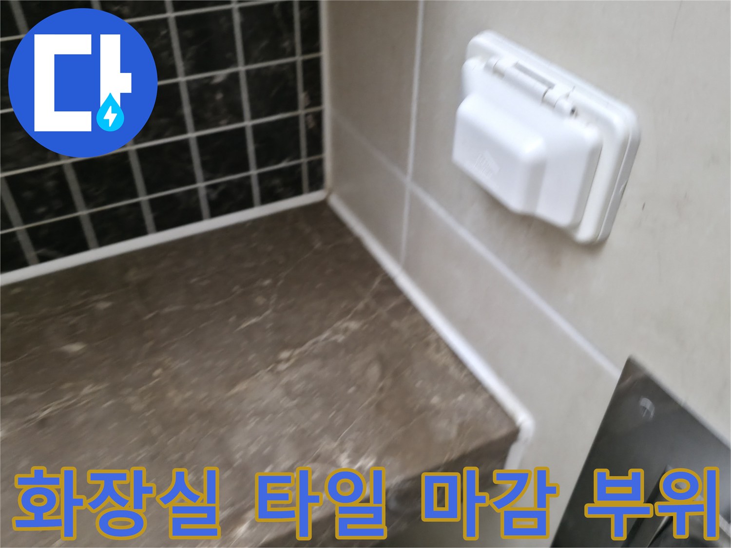욕실 내부의-어두운색 타일과-배관 주변 콘센트