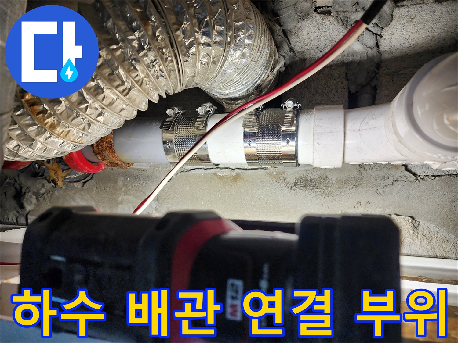 배관 연결부의 금속 밴드와 PVC 부속을 클로즈업한 사진입니다.