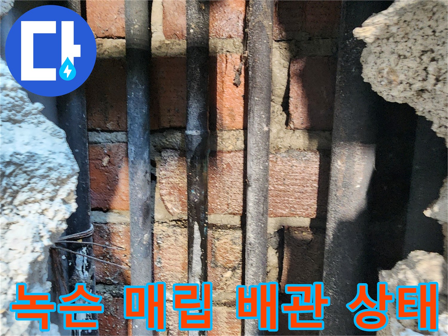 벽돌 구조물 사이의 부식된 금속 관로 사진