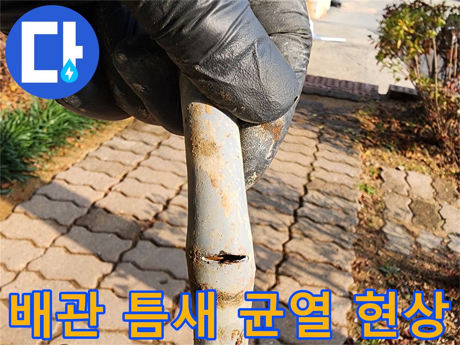 배관의 갈라진 틈을 손으로 가리키며 보여주는 사진