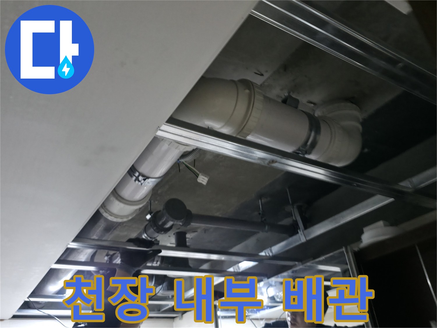 천장 프레임 사이에 위치한 대형 오수 배관의 근접 촬영