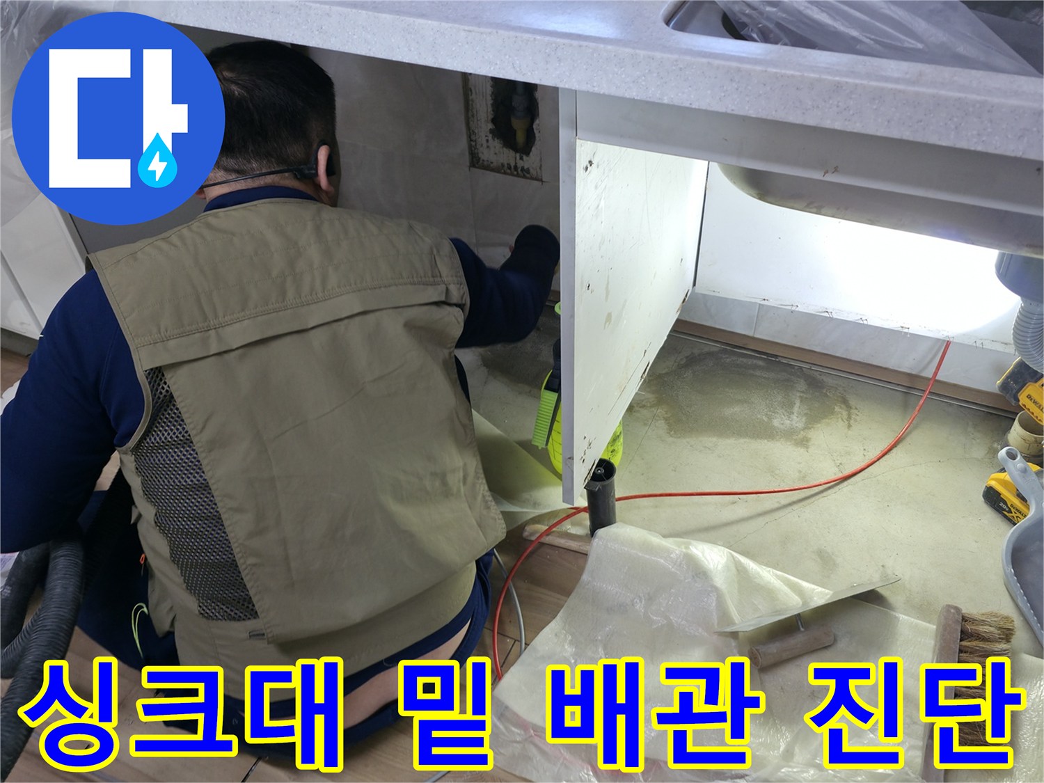 싱크대 하부 공간에서 벽면 배관의 누수 여부를 확인하고 있습니다.