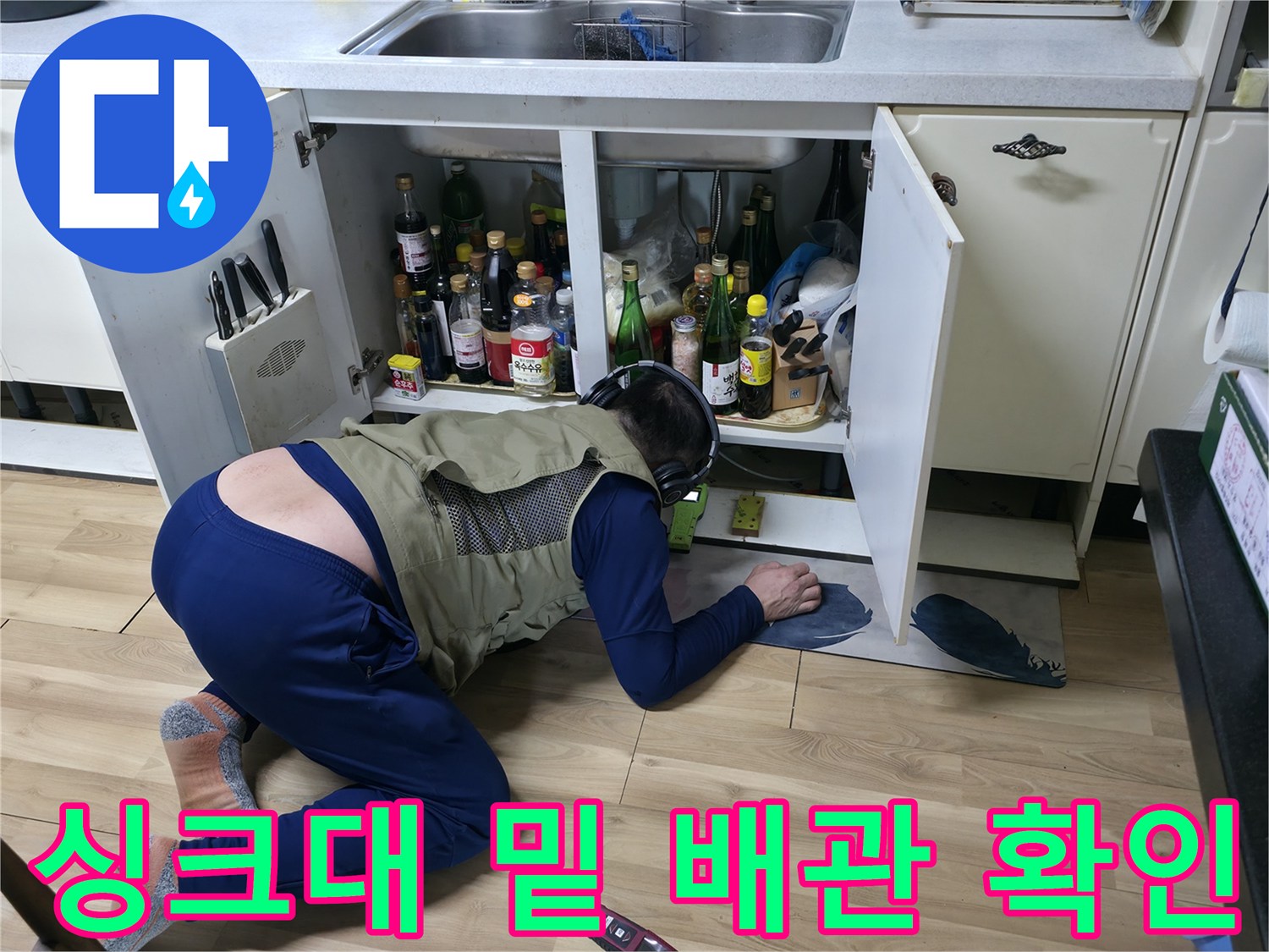 싱크대 하부장 바닥 쪽을 향해 몸을 숙여 배관 누수를 점검하는 모습
