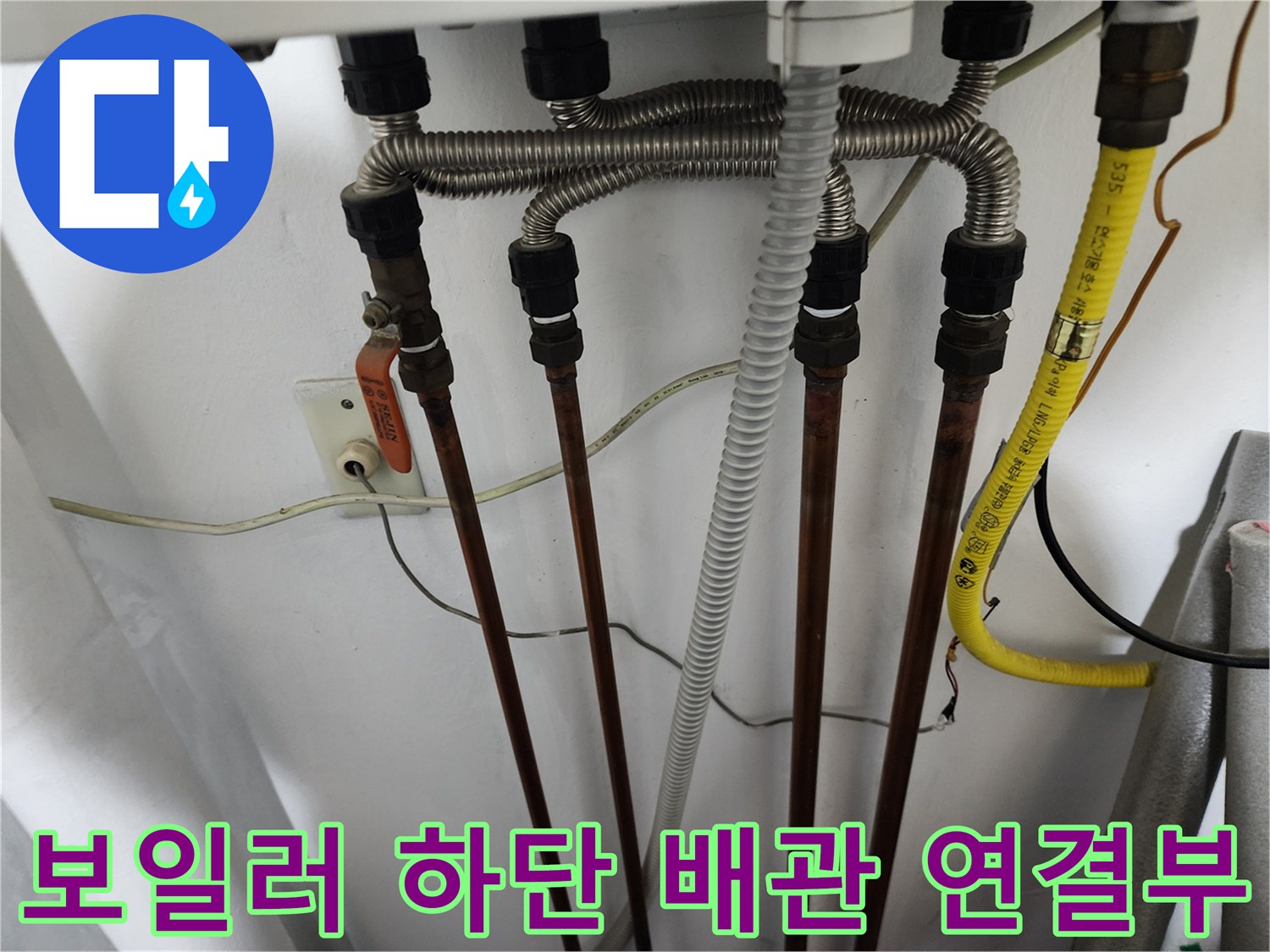 보일러 아래쪽의 은색 주름관과 동배관이 교차하는 모습