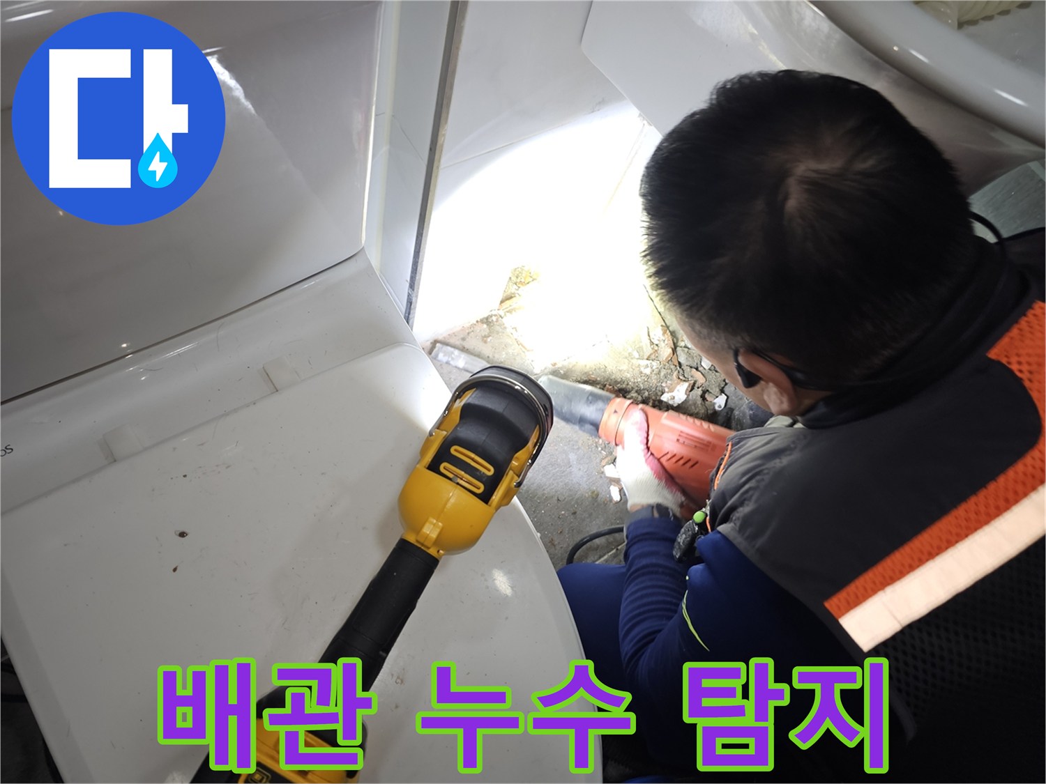 손전등을 사용하여 변기 뒤쪽 매립 배관 부위를 비추는 장면