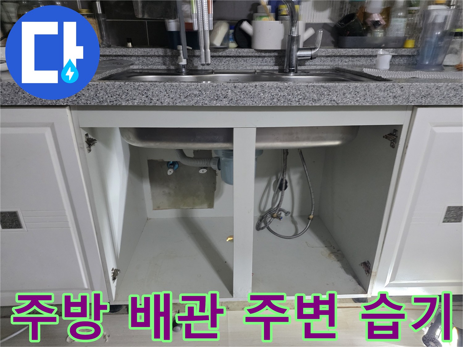 싱크대 하부장 내부의 젖은 바닥과 연결 배관 모습