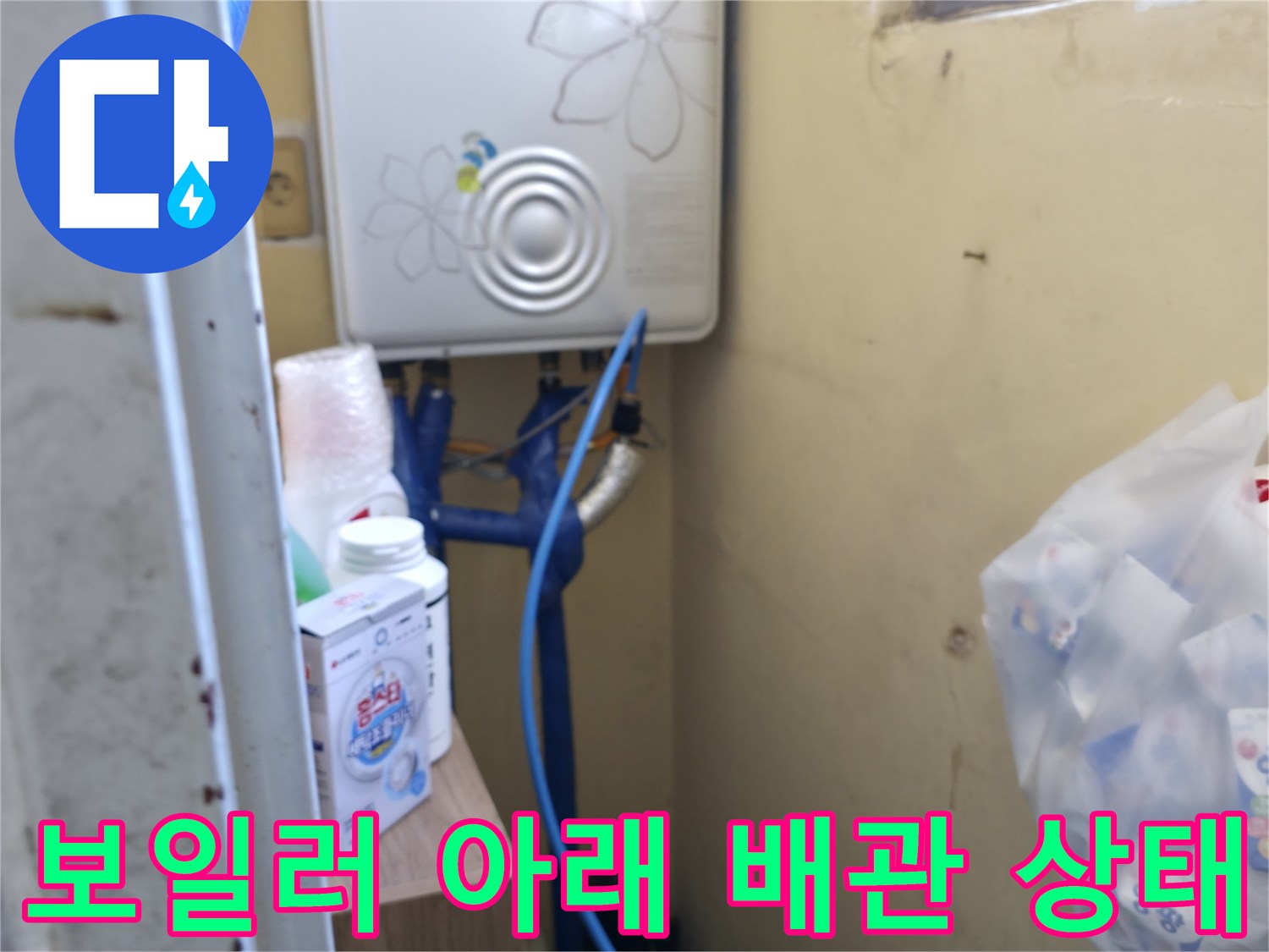 보일러 하단에 연결된 파란색 배관과 벽면 모습