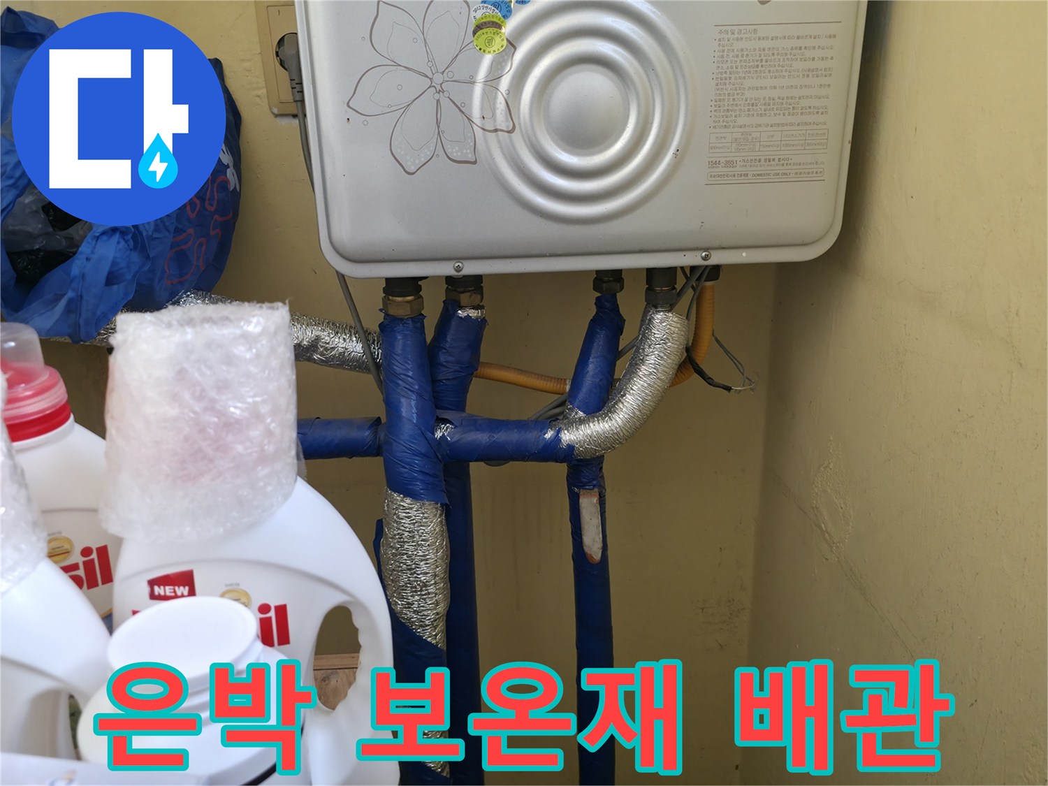 보일러 하부의 파란색 배관과 은색 보온재 마감 상태입니다.