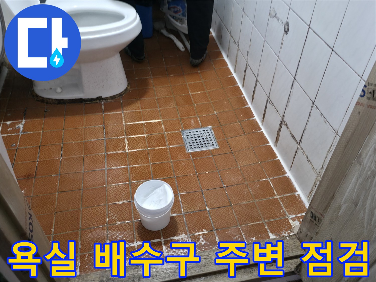 갈색 타일 바닥의 배수구와 변기 하단부 상세 모습