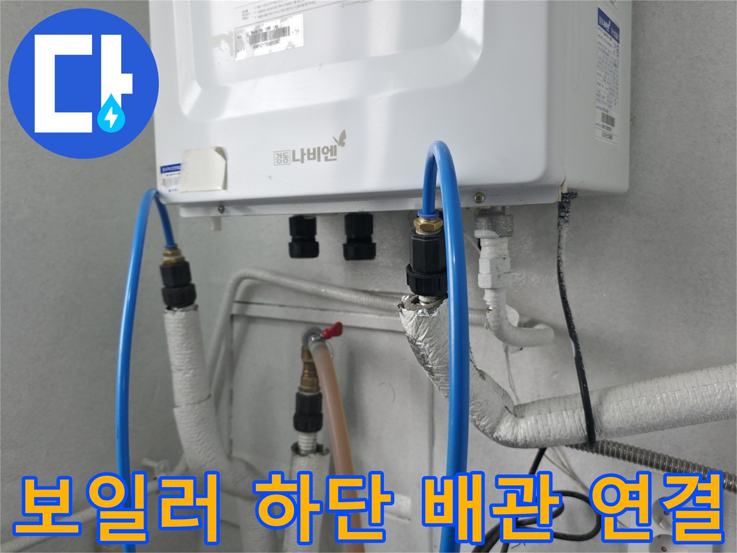 보일러 아래로 연결된 파란색 호스와 흰색 배관의 모습입니다.