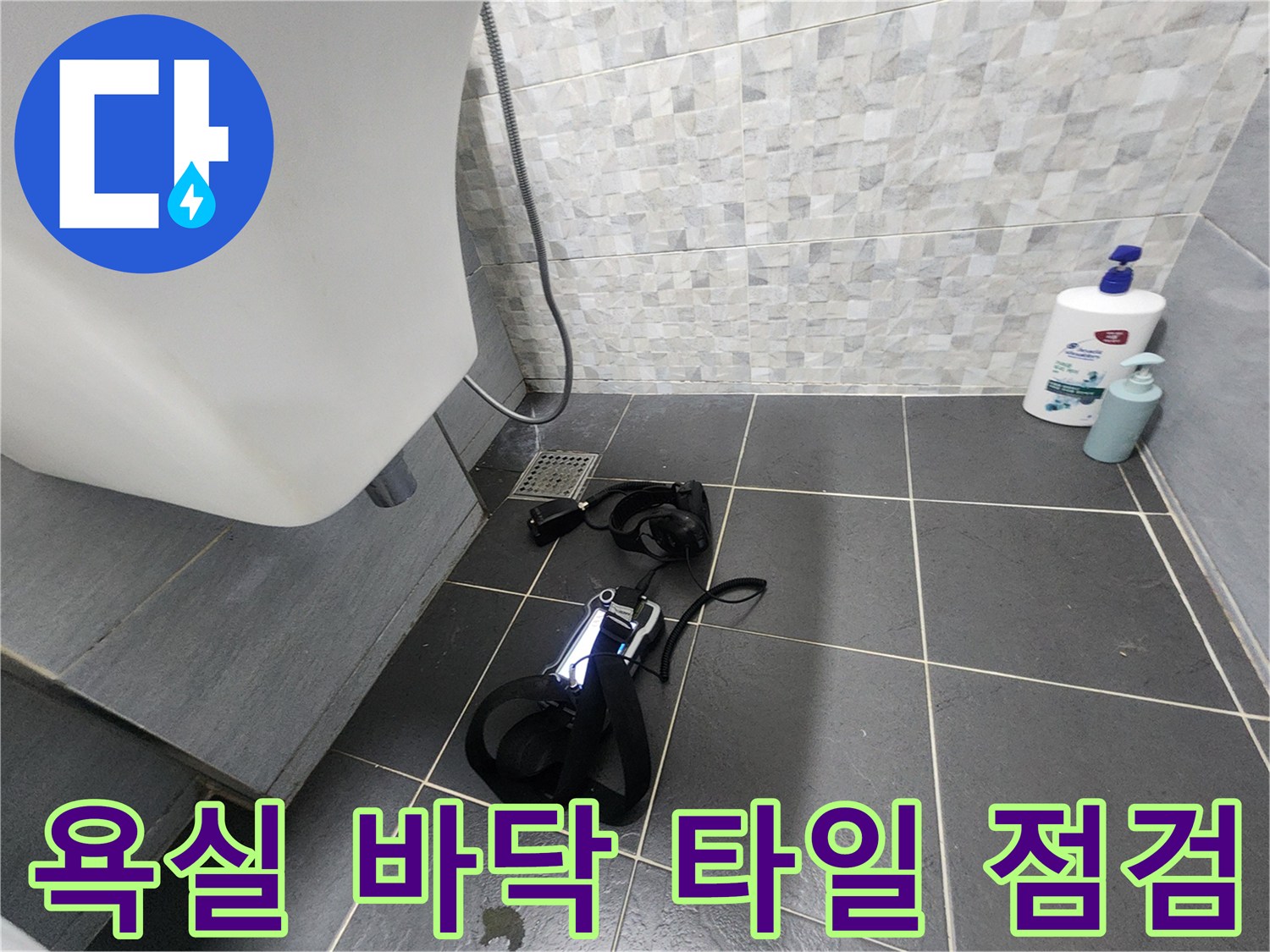 세면대 하단 배수구와 짙은 회색 타일 바닥의 누수 진단 상황