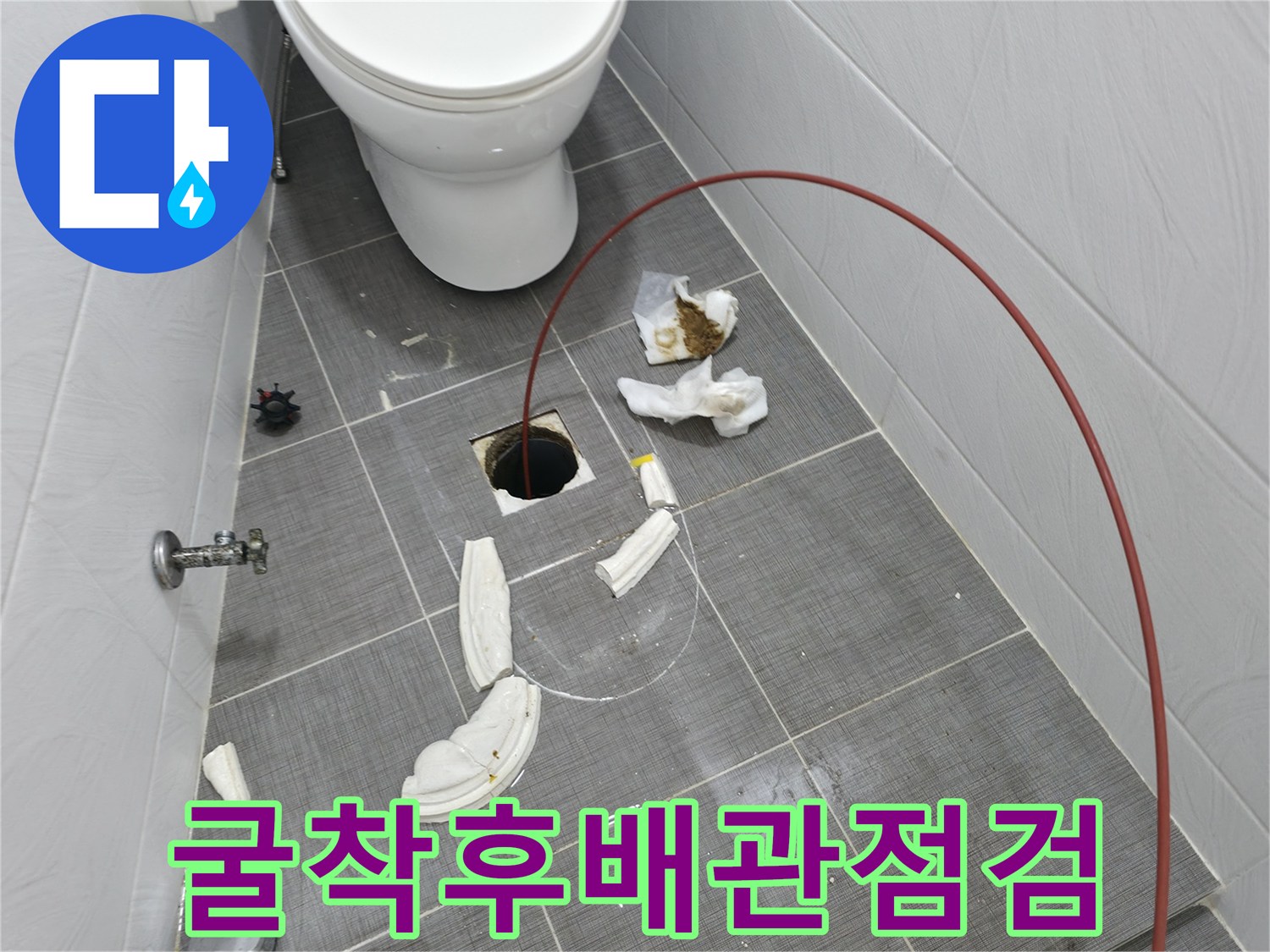 화장실 타일 굴착 후 드러난 파손 배관을 점검하는 공사 현장 사진