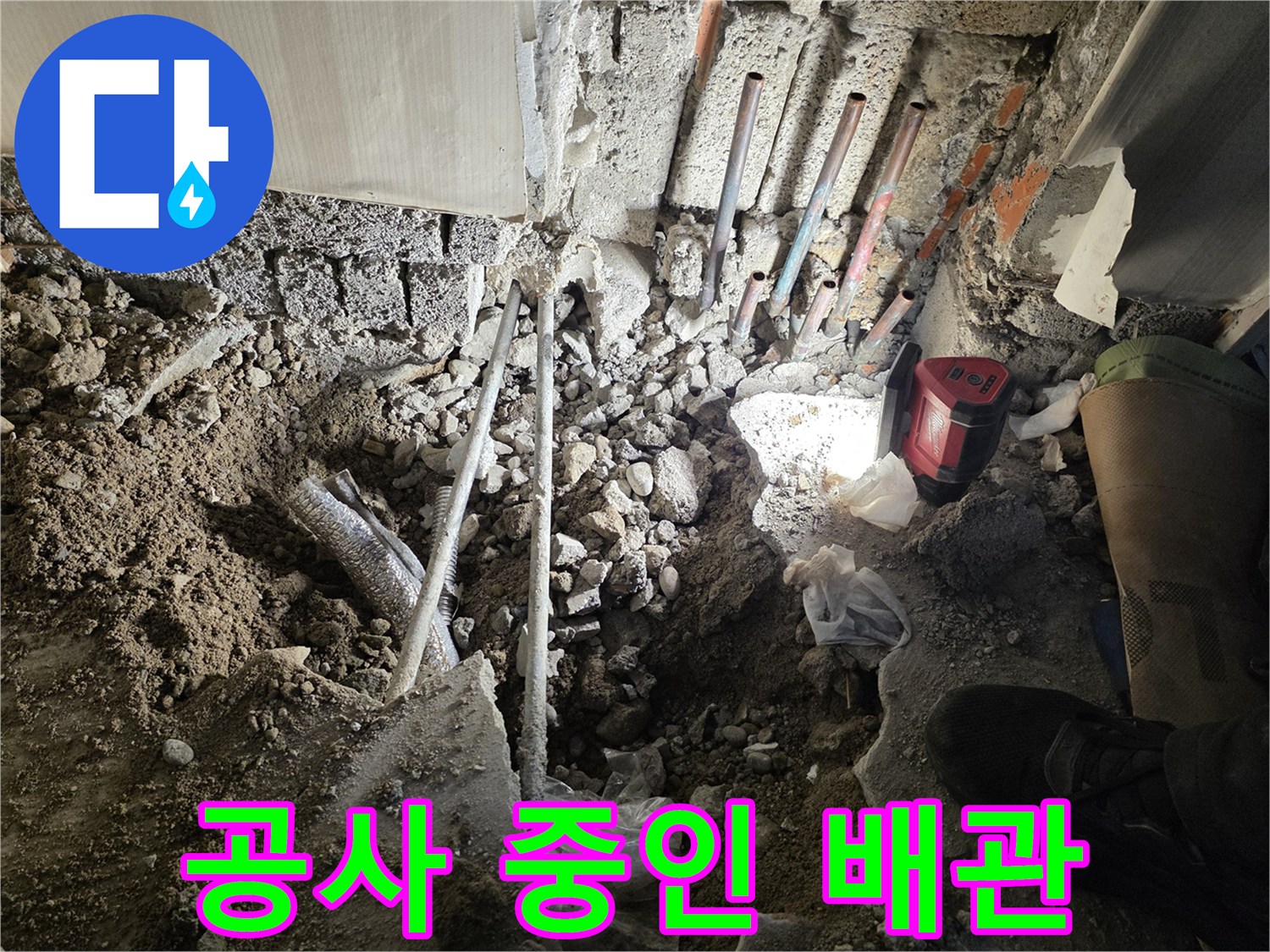 벽면 하단에 노출된 여러 개의 금속 배관과 흙