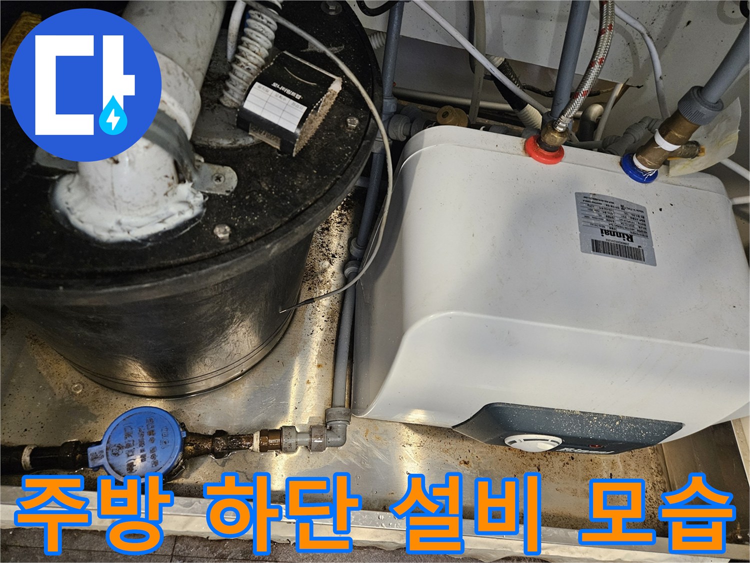 싱크대 아래 설치된 온수기와 복잡한 급수 배관의 상세 사진입니다.