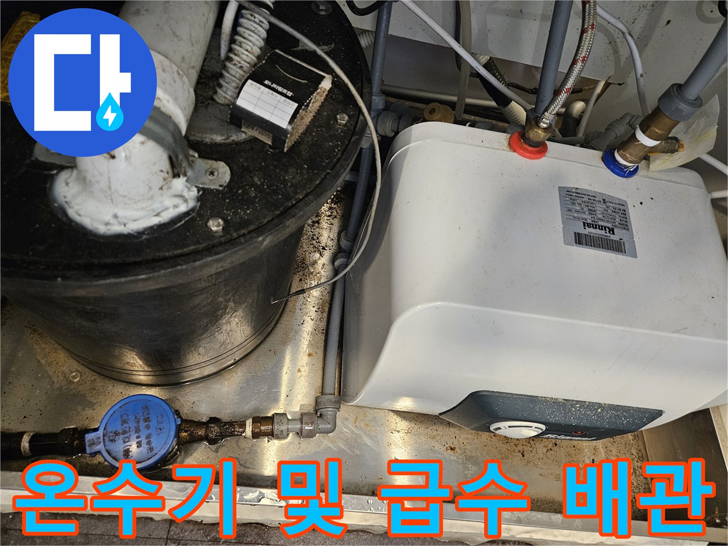 싱크대 아래 위치한 온수기와 수도 배관의 연결 상태를 보여주는 사진입니다.