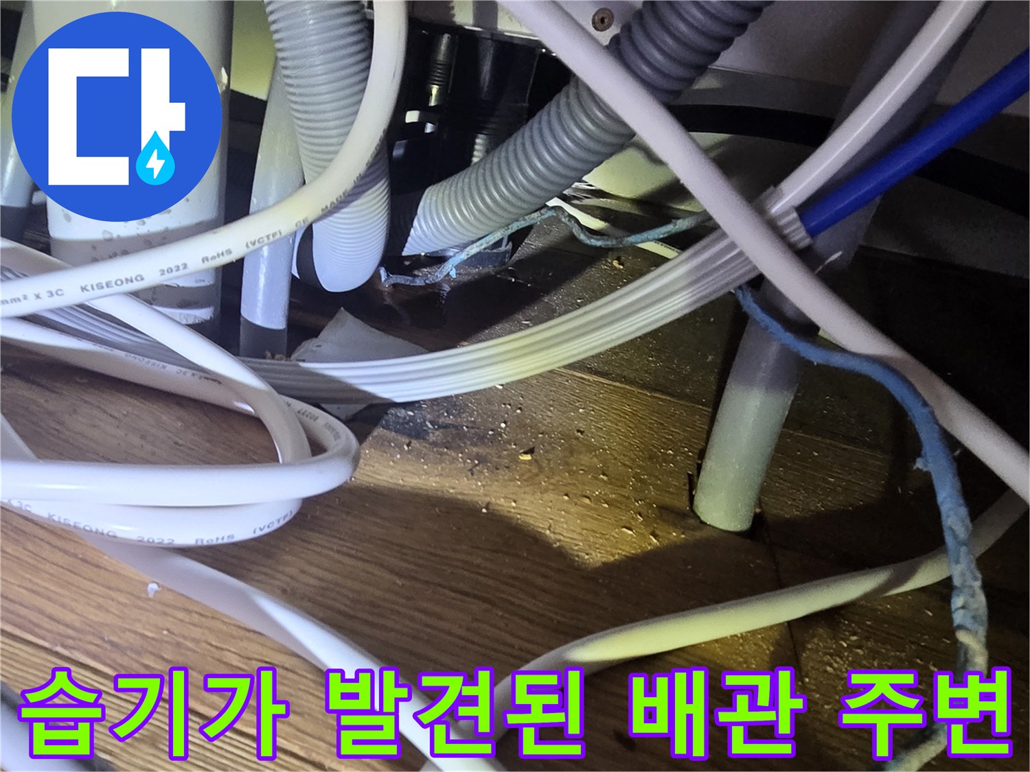 복잡하게 얽힌 싱크대 하단 배관과 젖은 바닥재 상태