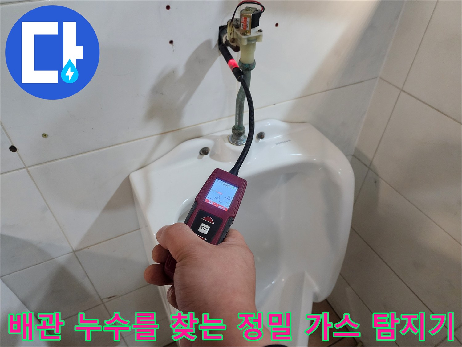 변기 뒤쪽 배관 부근에 가스 탐지기를 대고 누설 여부를 점검하는 장면입니다.