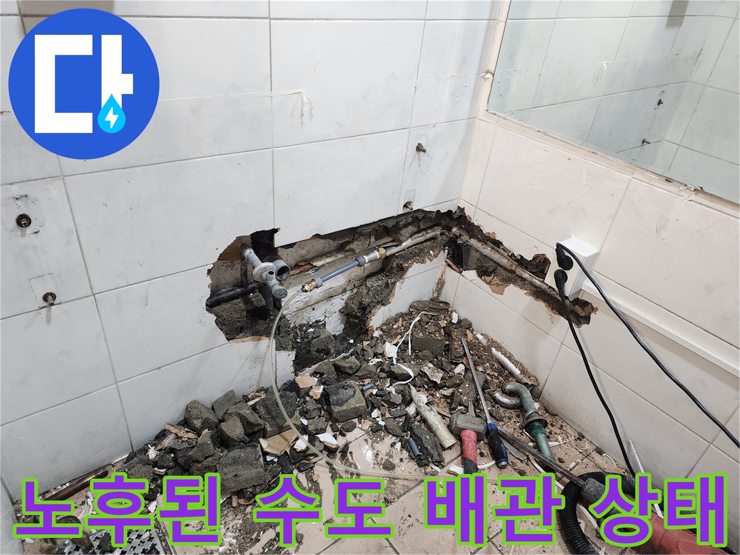 타일 아래 드러난 검은색 부식 배관과 작업 도구들