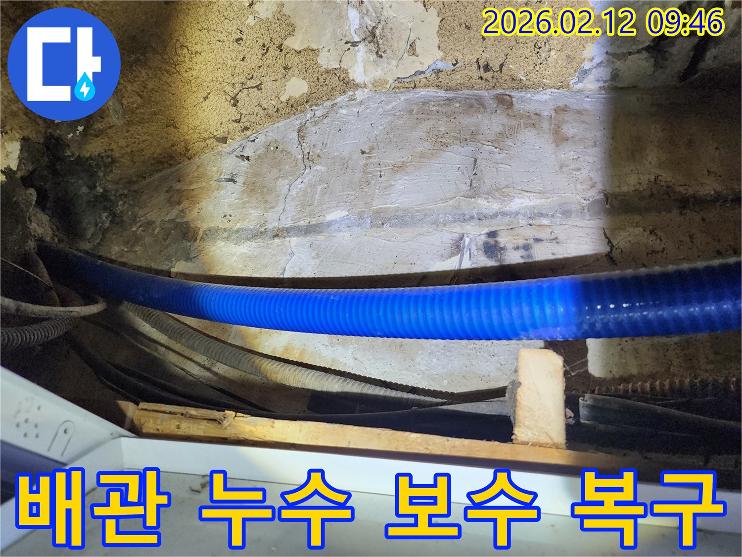 공장 내부의 낡은 벽면과 파란색 배관-주변의 누수 지점을 보수하고-손상된 시설을 복구하는 전문가의 작업 모습입니다.