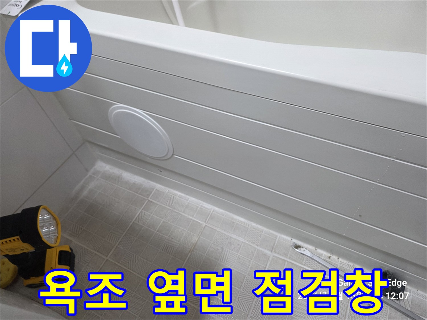 하얀색 욕조 벽면에 위치한 원형 모양의 점검창 사진입니다.