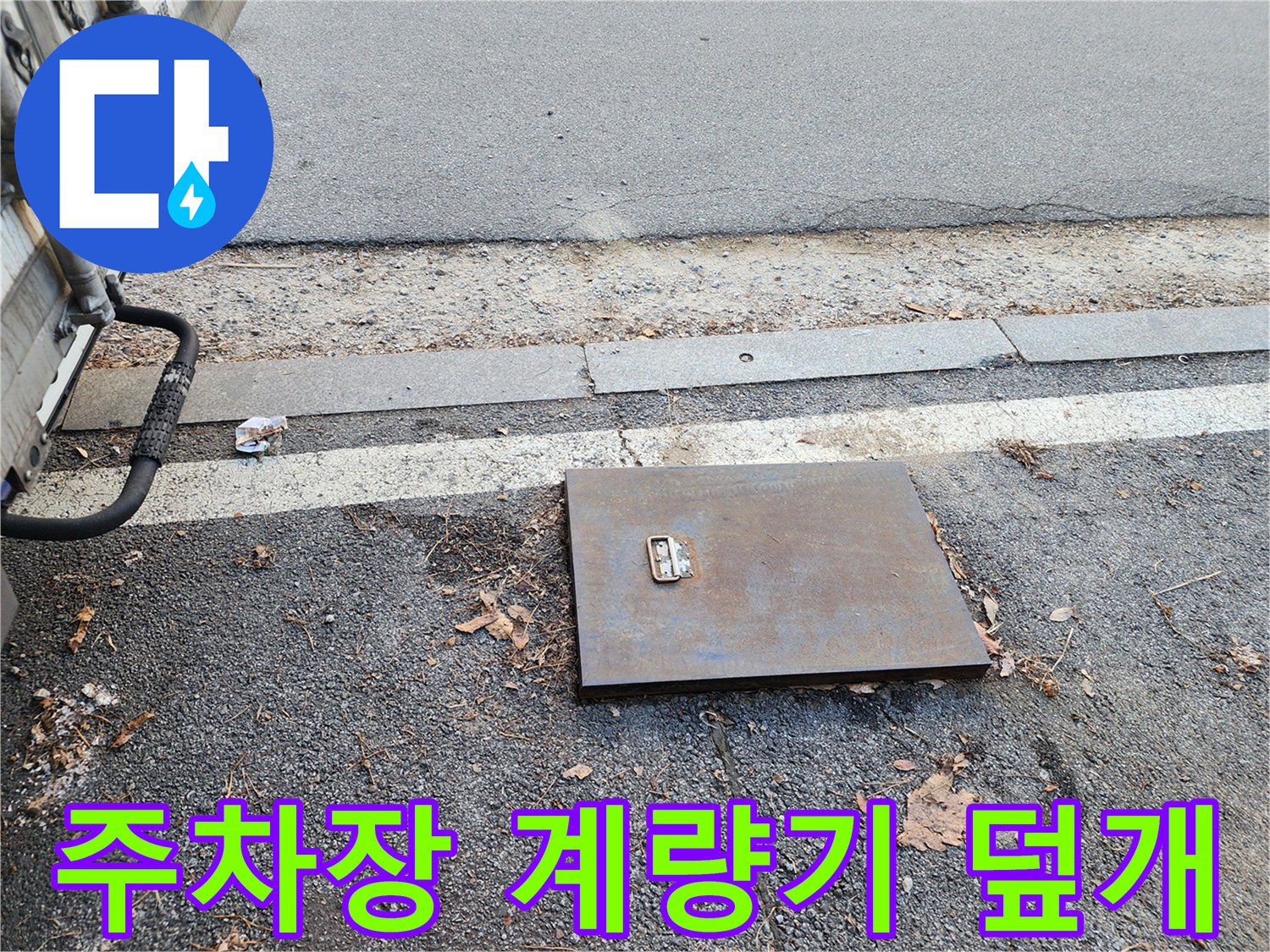 주차장 바닥에 설치된 금속 재질의 수도 계lam기 함 덮개 모습입니다.