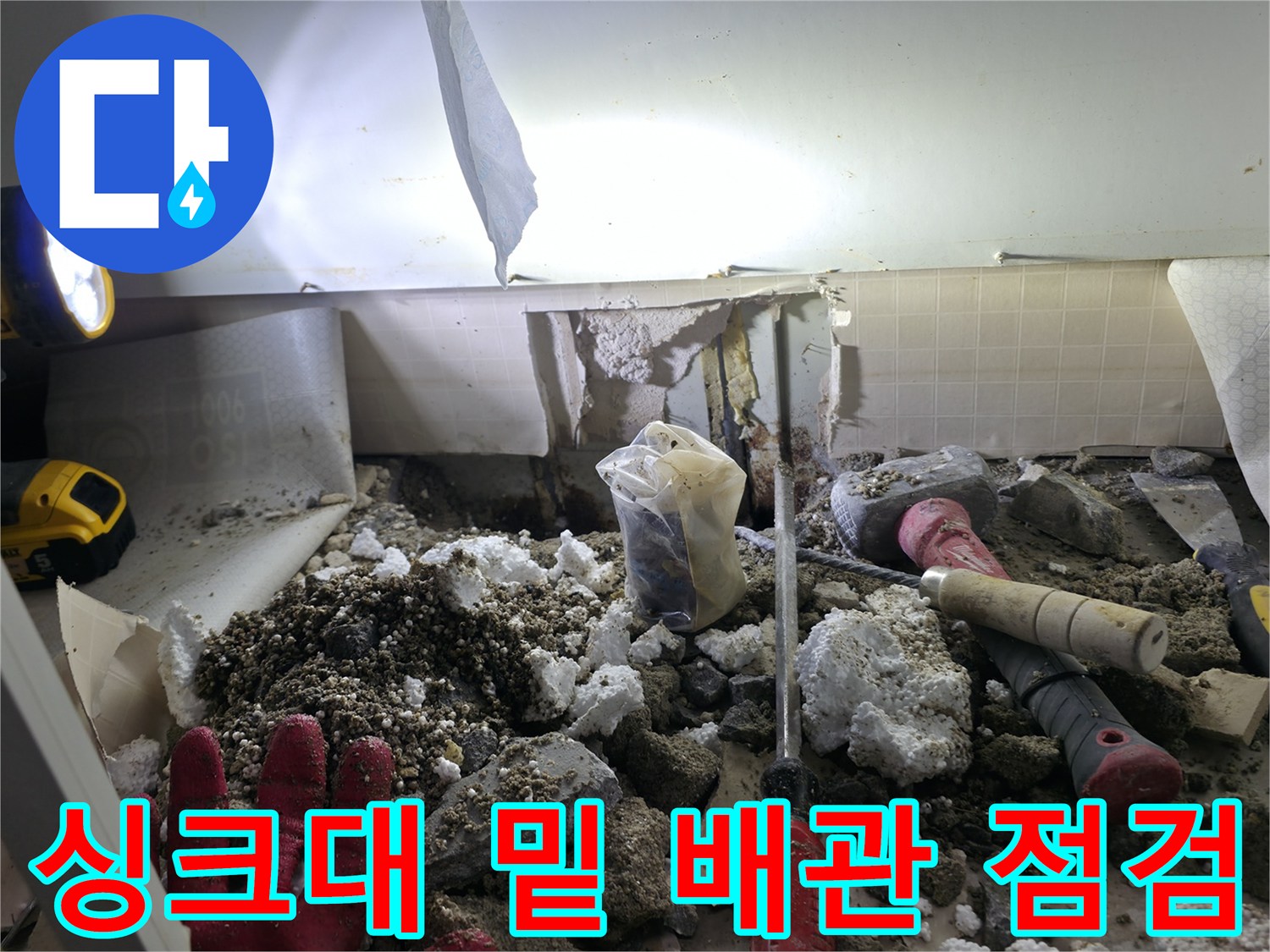 배관 파손 부위를 찾기 위해 싱크대 하부 바닥을 걷어낸 작업 현장입니다.