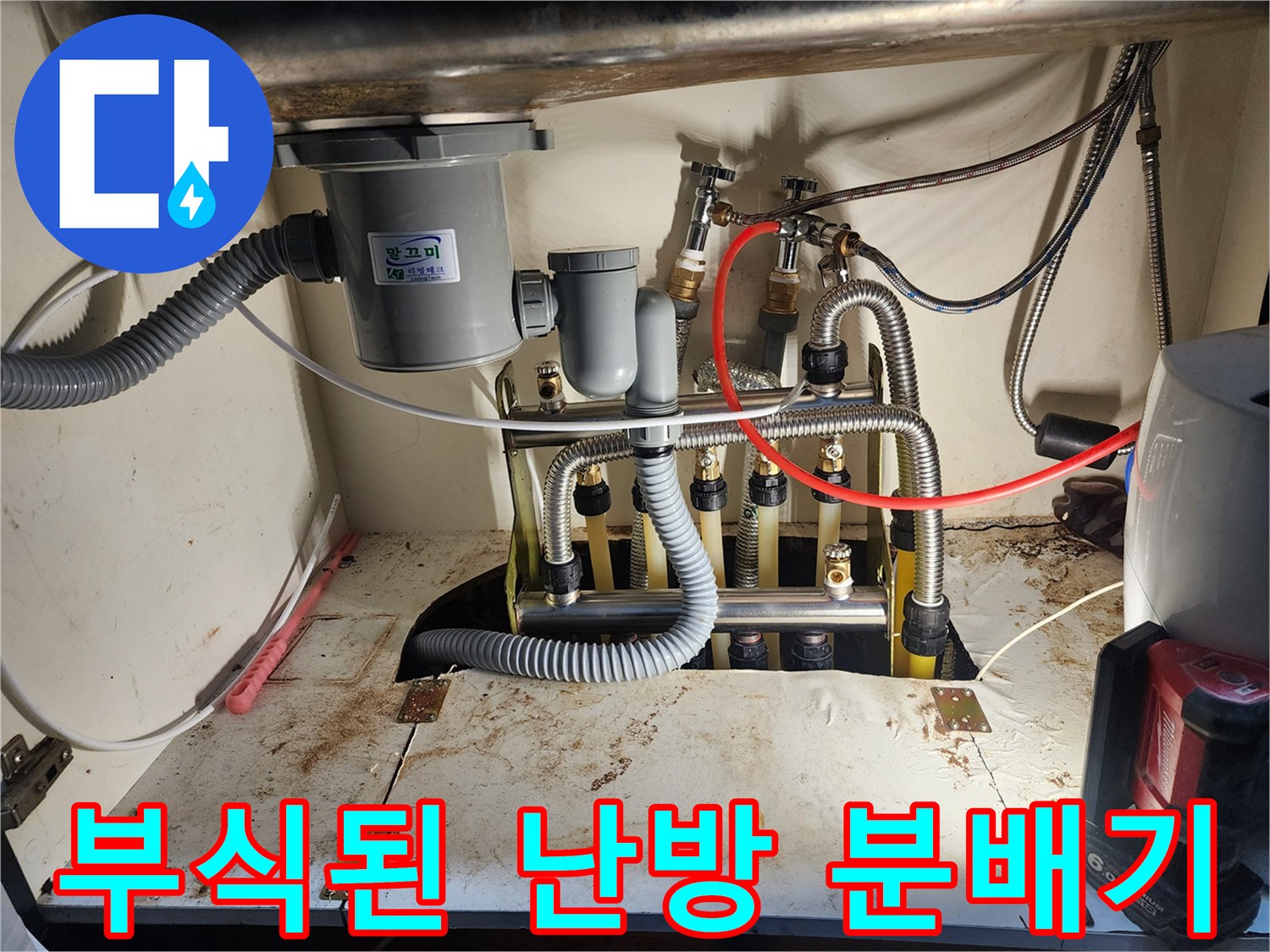 싱크대 아래 공간에 위치한 - 부식된 금속 난방 분배기 모습