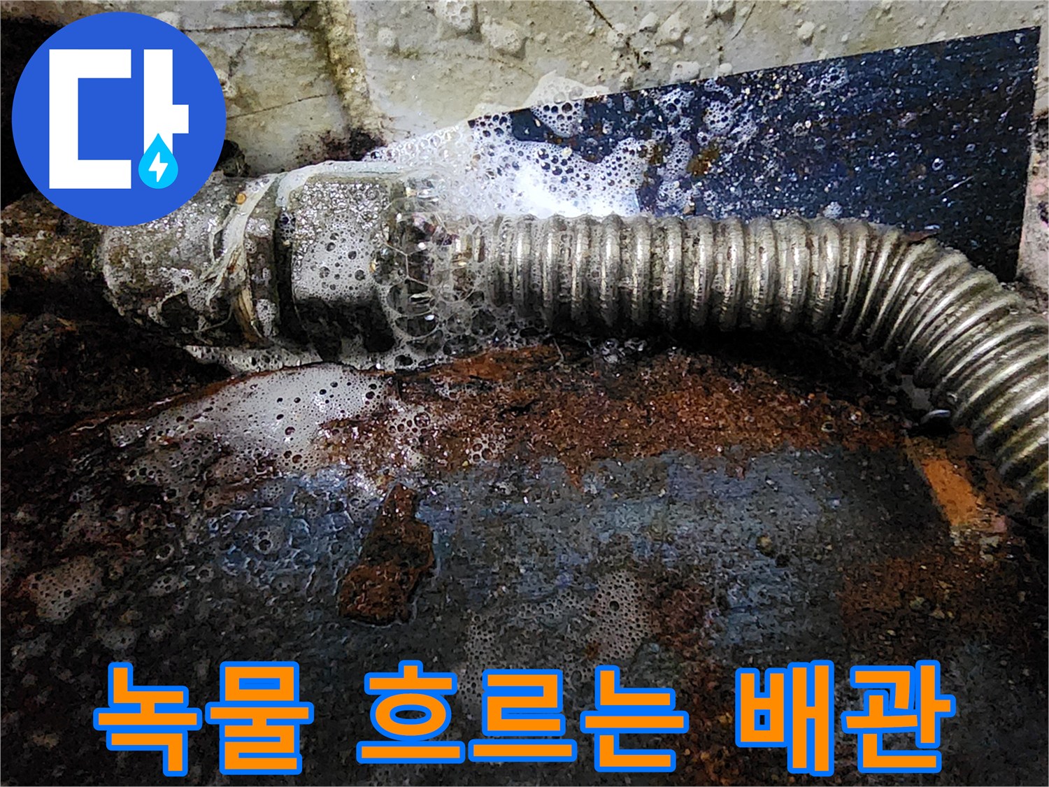 붉은 녹과 함께 물이 새어 나오는 노후된 배관 모습