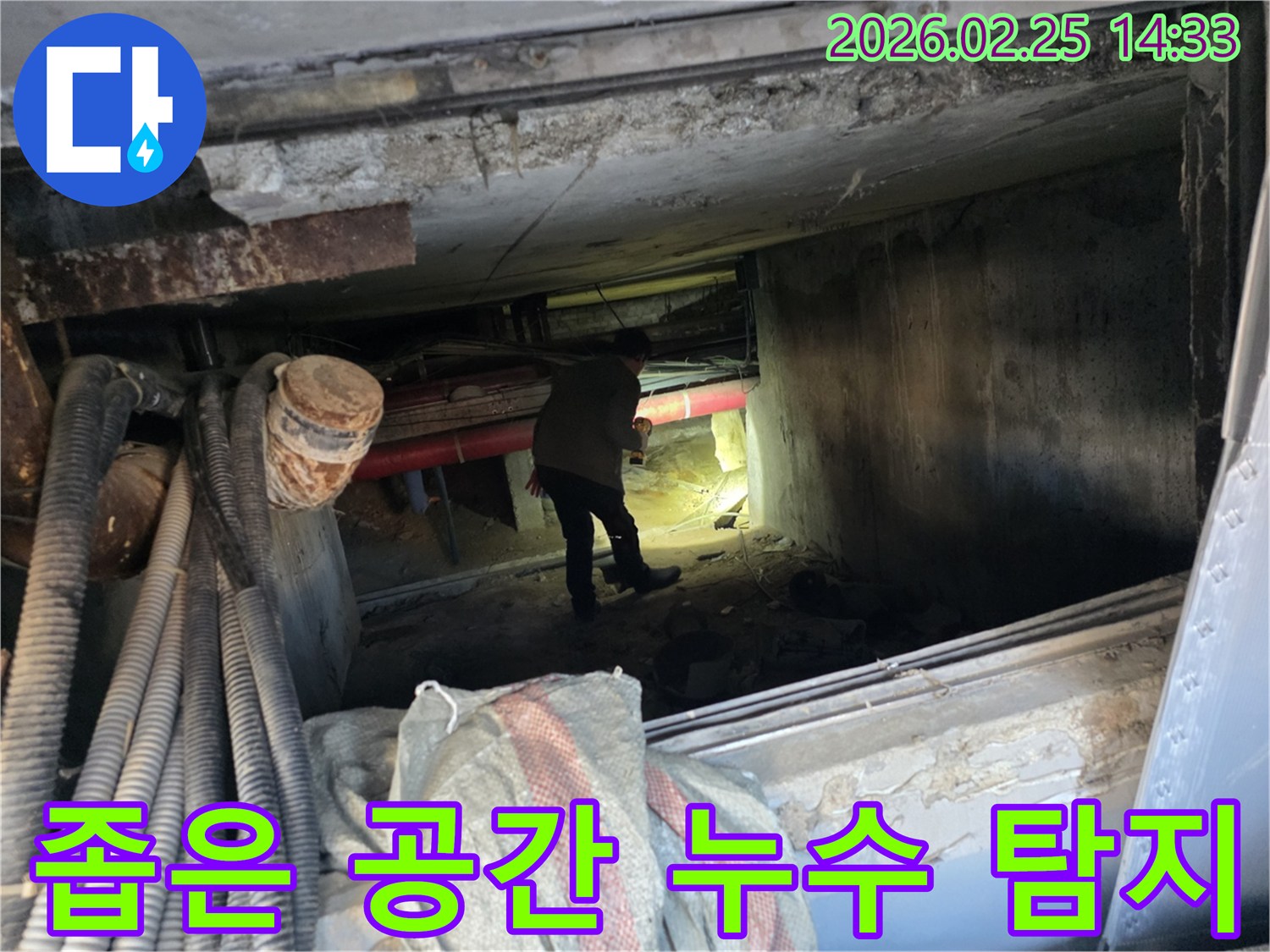 누수 전문가가-손전등을 비추며-배관이 복잡한-지하 통로를-조사하는 모습