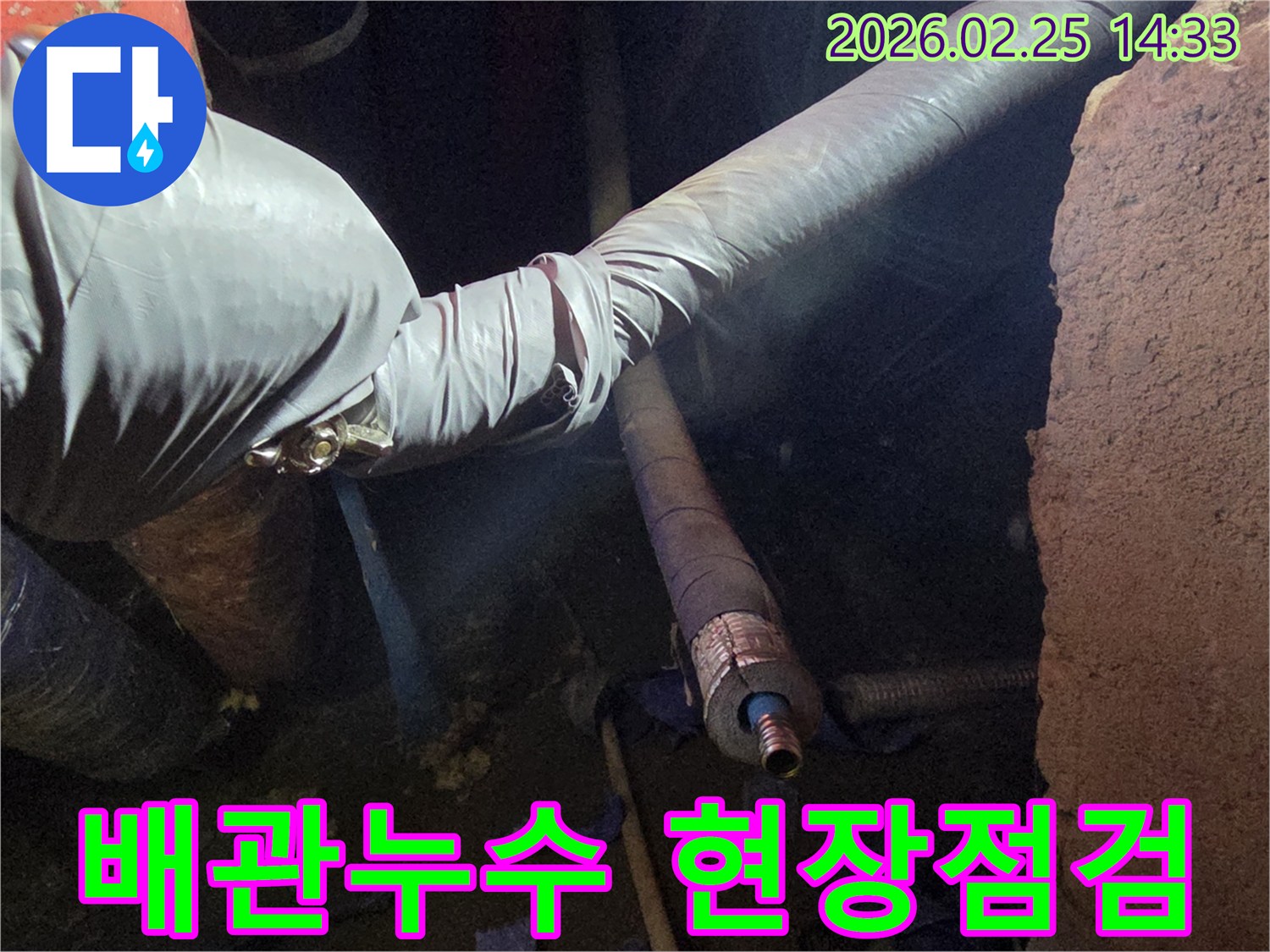 어두운 공간에서-숙련된 기술자가-장갑을 끼고-손상된 배관의-연결 부위를-정밀하게 점검하는-수리 작업 현장입니다