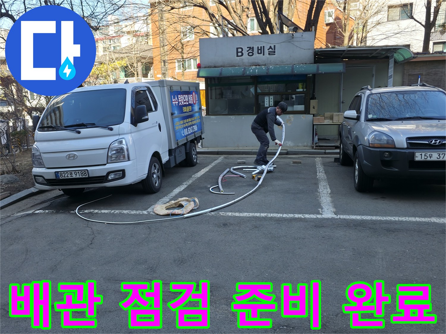 작업 차량 옆에 놓인 긴 호스와 지하 배관실 출입구 주변