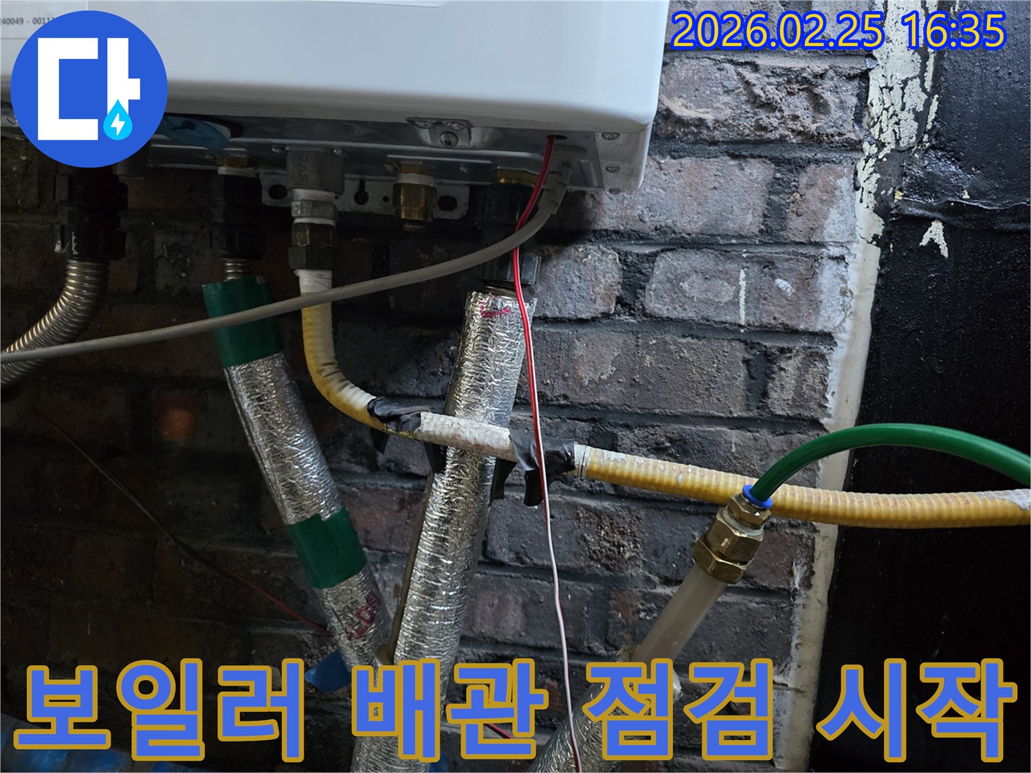 이 이미지는-벽에 설치된-보일러 하단부의-다양한 배관과-전선-그리고-단열재가-감싸진-모습을-보여주며-누수 점검의-초기 단계를-나타냅니다.