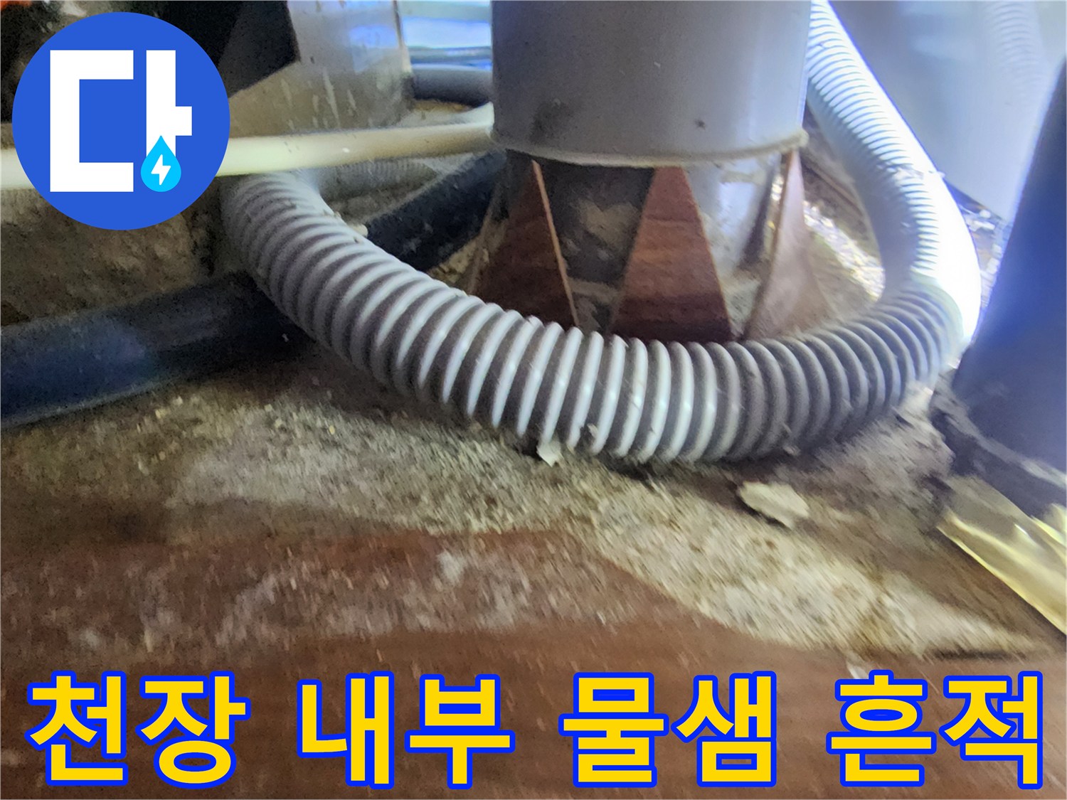 물에 젖어 변색된 나무 판재와 회색 주름 배관