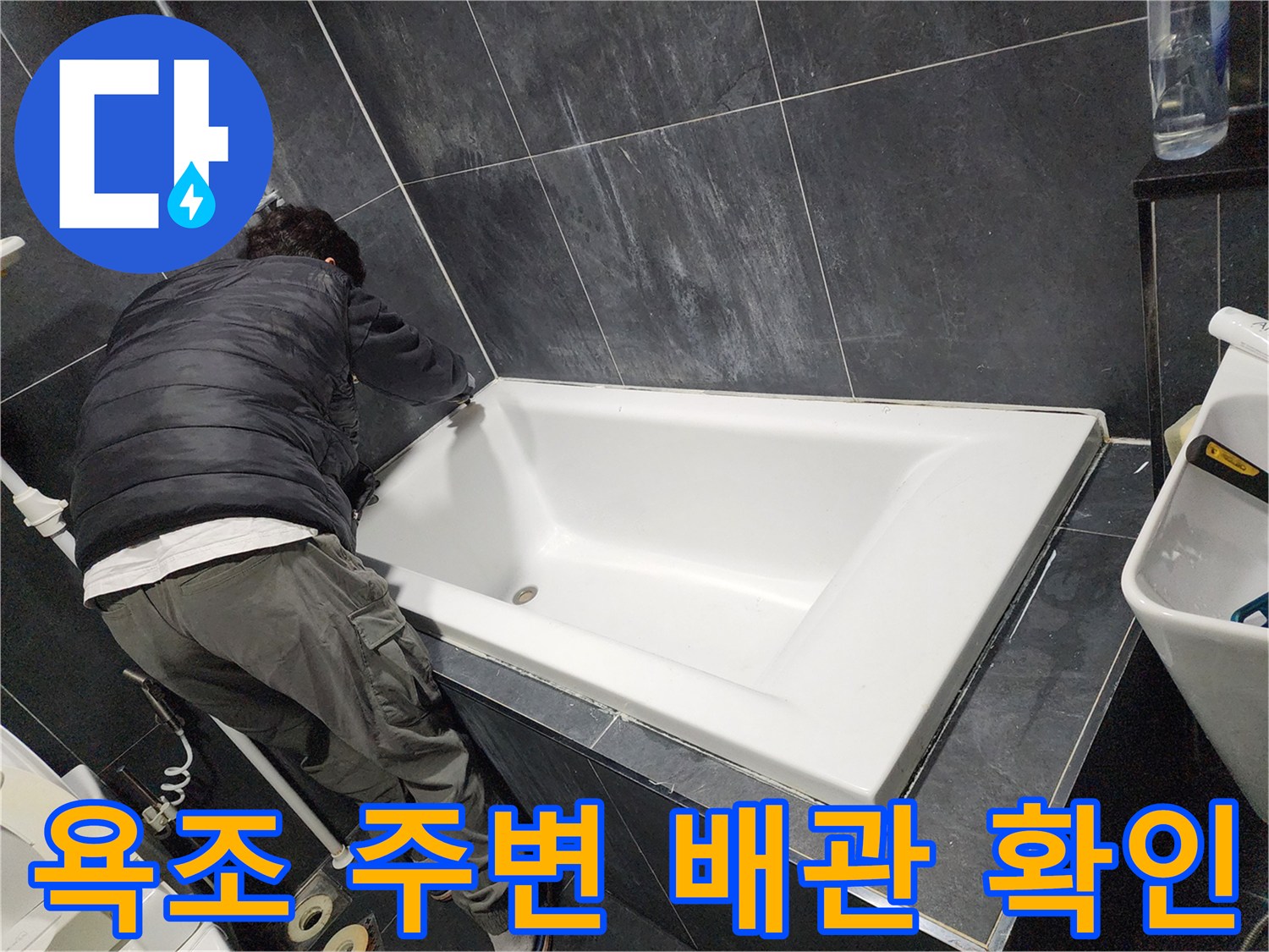 욕조 하단 틈새를 통해 배관을 점검하는 작업자