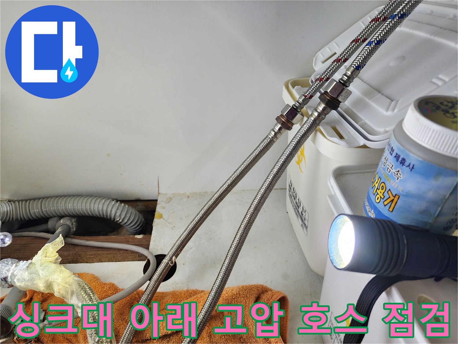 손전등 빛이 비치는 은색 꼬임 배관과 연결 부위의 모습