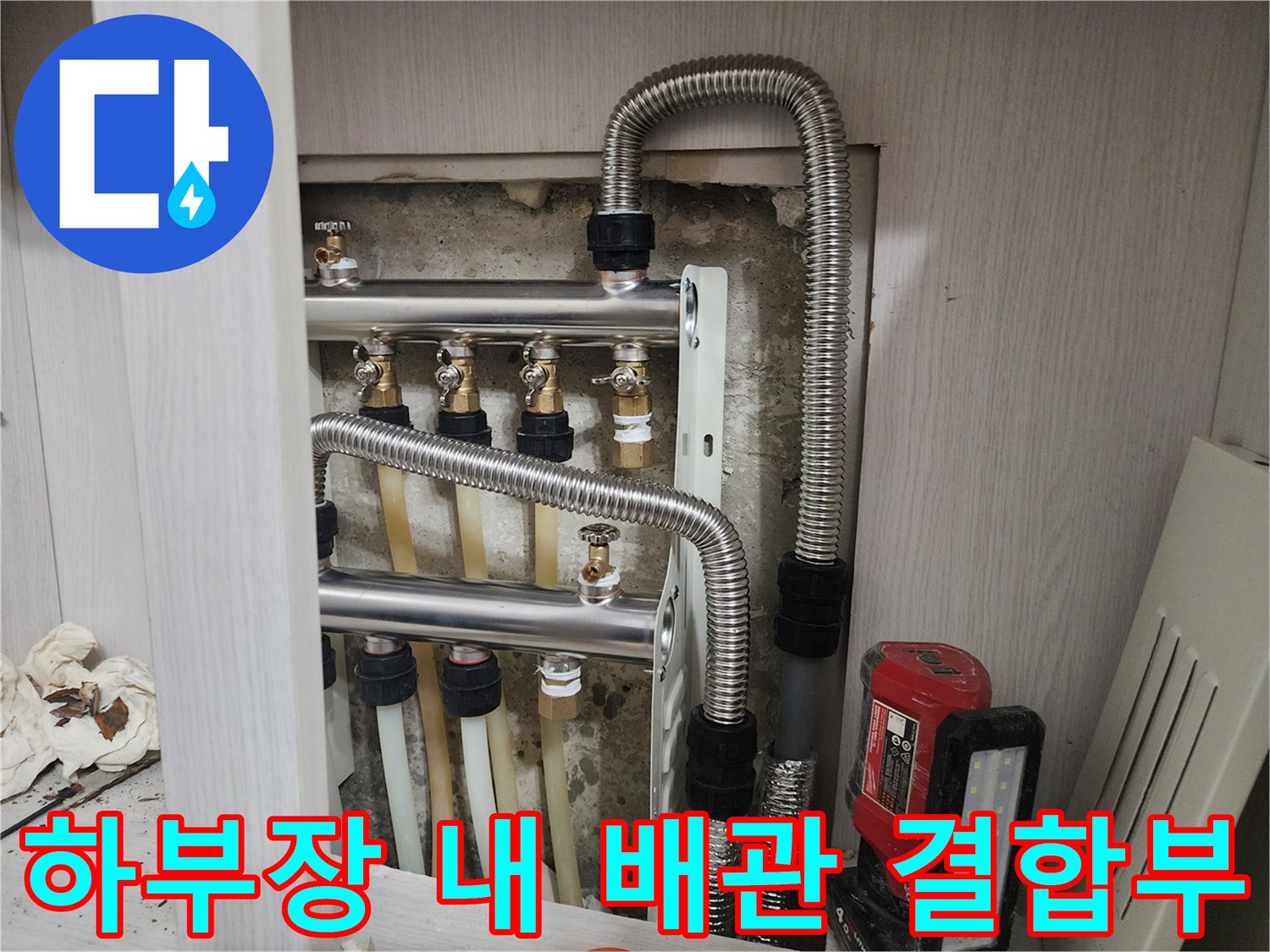 주방 싱크대 아래 설치된 은색 금속 배관과 부속품들