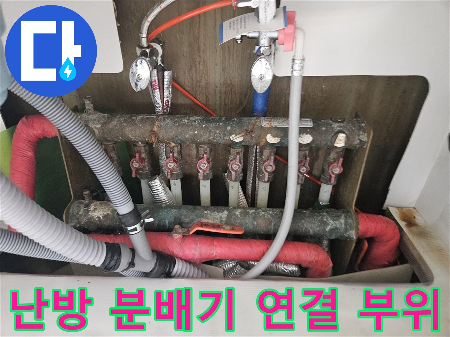 부식된 동배관과 밸브가 복잡하게 연결된 난방 분배기 모습입니다.